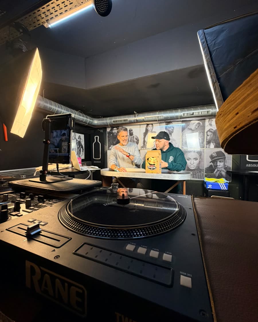 Zwei Moderatoren am Tisch waehrend der ersten Live Show, Produkte und Laptop vor ihnen